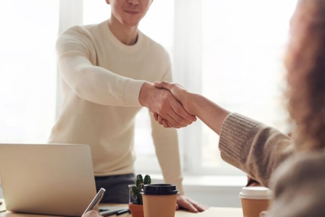 a landlord in a white shirt reaches over their desk to shake the hand of their new tenant | Specialized Indianapolis a landlord in a white shirt reaches over their desk to shake the hand of their new tenant