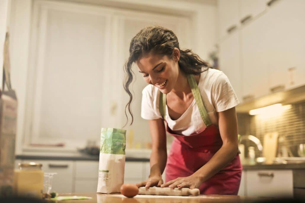 pexels-olly-3769999 | Specialized Indianapolis woman in red apron rolling out dough in home kitchen