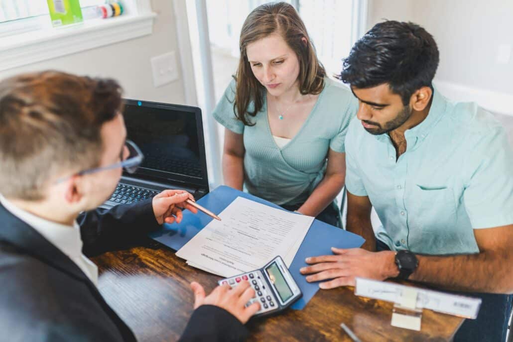 pexels-rdne-8293651 1 | Specialized Indianapolis couple sitting at a desk with a man in a suit who is showing them documents and using a caculator